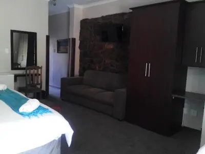 a living room with a couch and a television at Gabbata Lodge in Leeuwfontein