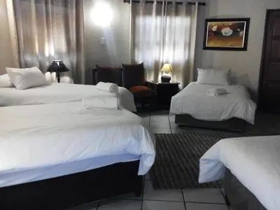 a hotel room with two beds and a chair at Gabbata Lodge in Leeuwfontein