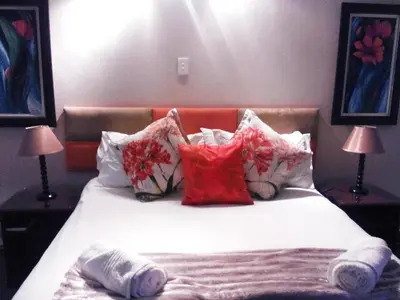 a bedroom with a bed with pillows and two lamps at Gabbata Lodge in Leeuwfontein