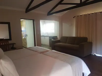 a bedroom with a large bed and a couch at Gabbata Lodge in Leeuwfontein