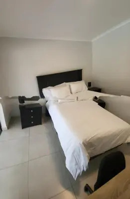 a bedroom with a large white bed and a chair at Limewood 2 in Sandton