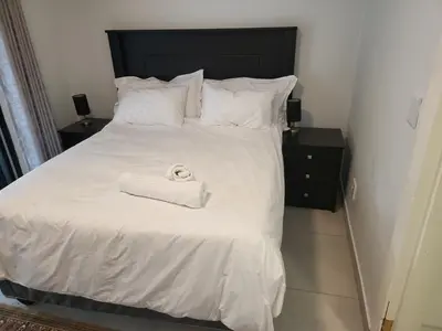 a bed with white sheets and a towel on it at Limewood 2 in Sandton