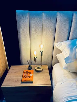 a bed with a table with two lamps and a book at The Blyde Pretoria 2 bed 2 bath apartment in Pretoria