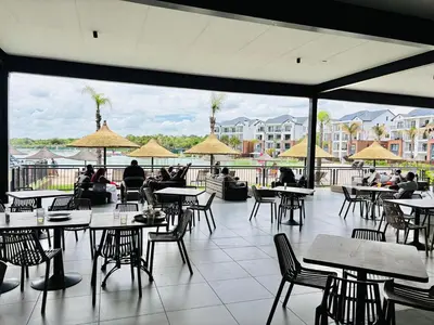 a restaurant with tables and chairs and people sitting at tables at The Blyde Pretoria 2 bed 2 bath apartment in Pretoria