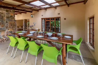 a large wooden table and green chairs in a room at Misty Mountain in Sabie