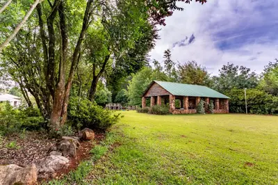 a barn in a field next to a tree at Misty Mountain in Sabie