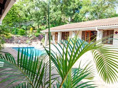 a house with a swimming pool next to a building at Sabores Lodge and Restaurant in Nelspruit