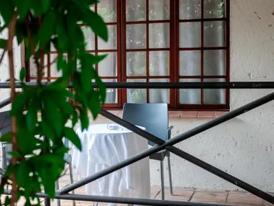 a table and a chair in front of a window at Sabores Lodge and Restaurant in Nelspruit