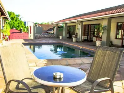 a table and two chairs next to a swimming pool at Sabores Lodge and Restaurant in Nelspruit