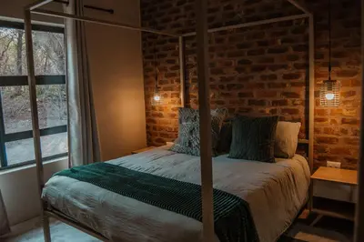 a bedroom with a four poster bed with a brick wall at The Hyde in Marloth Park