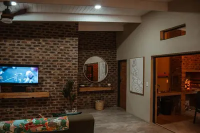a living room with a couch and a tv on a brick wall at The Hyde in Marloth Park
