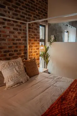 a bed in a room with a brick wall at The Hyde in Marloth Park