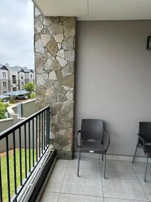 two chairs sitting on a balcony with a stone wall at Home at Polo - Classy Comfort in Midrand