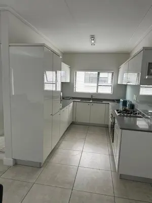 a kitchen with white cabinets and a tile floor at Home at Polo - Classy Comfort in Midrand