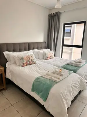 a large white bed with towels on top of it at Home at Polo - Classy Comfort in Midrand