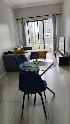 a living room with a couch and a table and chairs at The Luxury Apartments in Midrand