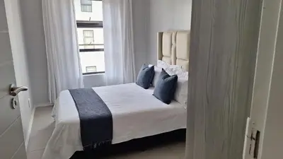 a bed with blue pillows in a room with a window at The Luxury Apartments in Midrand