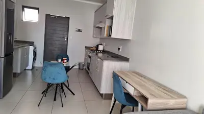 a kitchen with two blue chairs and a wooden table at The Luxury Apartments in Midrand