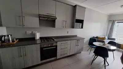 a kitchen with a stove and a table with chairs at The Luxury Apartments in Midrand