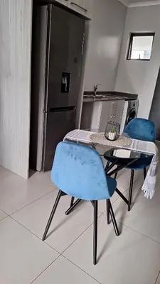 a kitchen with a table and two chairs and a refrigerator at The Luxury Apartments in Midrand