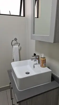 a bathroom with a white sink and a mirror at The Luxury Apartments in Midrand