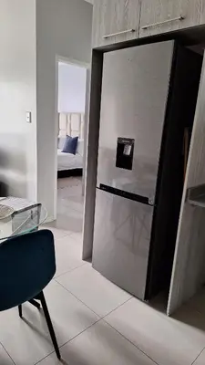 a kitchen with a refrigerator in the middle of a room at The Luxury Apartments in Midrand
