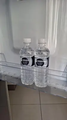 three bottles of water sitting on a shelf in a refrigerator at The Luxury Apartments in Midrand