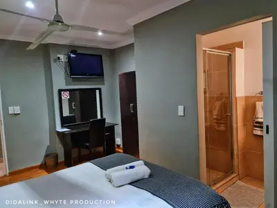 a bedroom with a bed and a desk and a television at Glen Rest Country Lodge in Midrand