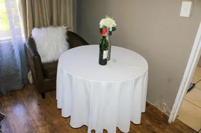 a bottle of wine on a table with a flower at Glen Rest Country Lodge in Midrand