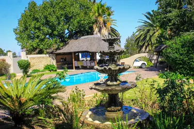 a fountain in front of a house with a pool at Glen Rest Country Lodge in Midrand