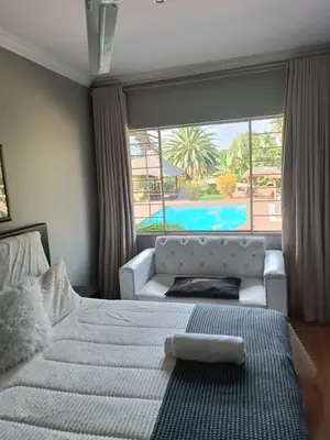 a bedroom with a bed and a view of a pool at Glen Rest Country Lodge in Midrand