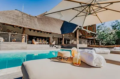 a table with a hat and glasses next to a pool at Bongela Private Game Lodge in Vaalwater
