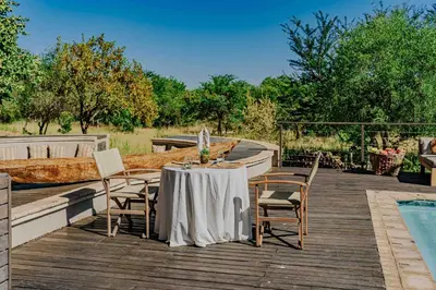 a table and chairs on a deck next to a pool at Bongela Private Game Lodge in Vaalwater