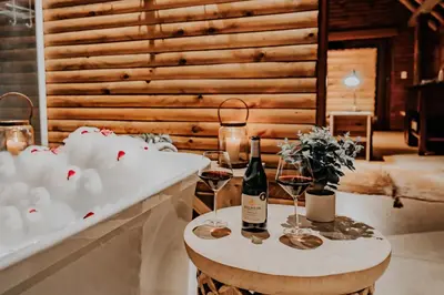 a table with two glasses of wine and a bath tub at Bongela Private Game Lodge in Vaalwater