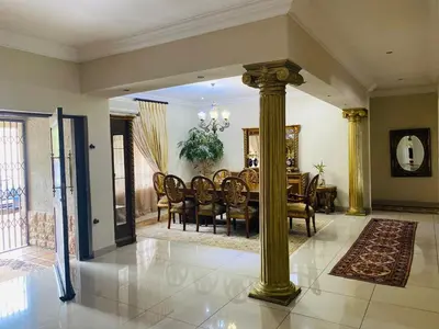 a dining room with a table and gold columns at The Adress in Midrand