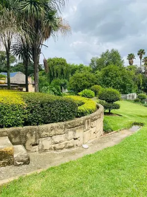 a retaining wall in a park with trees and grass at The Adress in Midrand