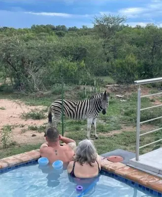 two people in a swimming pool with a zebra at Kings view exclusive villas in Petronella