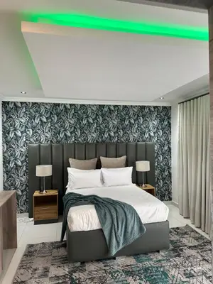 a bedroom with a large bed with a green light above it at Nouvelle Ere Beauty Spa & Boutique Guesthouse in Centurion