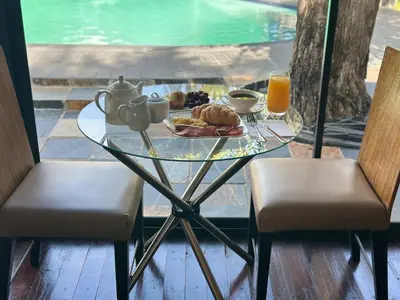 a glass table with a plate of food and orange juice at Nouvelle Ere Beauty Spa & Boutique Guesthouse in Centurion