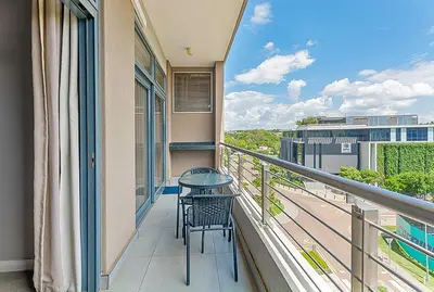 a balcony with a table and chairs on a building at Capital Residence Apartment in Menlyn Maine in Pretoria