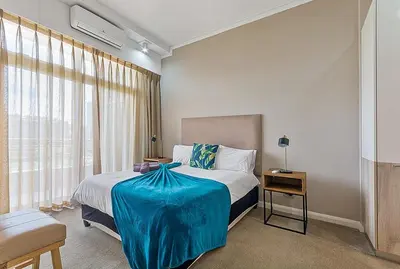 a bedroom with a bed with a blue blanket on it at Capital Residence Apartment in Menlyn Maine in Pretoria