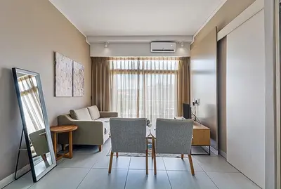 a living room with a couch and a table and chairs at Capital Residence Apartment in Menlyn Maine in Pretoria