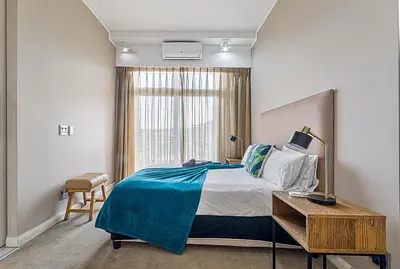 a bedroom with a bed and a desk and a window at Capital Residence Apartment in Menlyn Maine in Pretoria