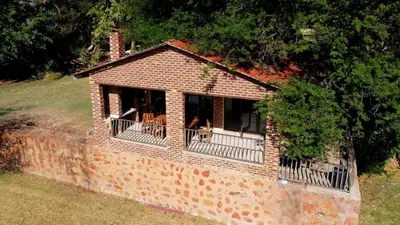 a small brick house with a porch and balcony at Riverside Lodge - Loerie in Cobalt