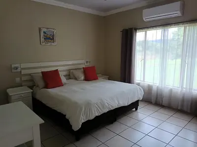 a bedroom with a bed with red pillows and a window at Riverside Lodge - Loerie in Cobalt