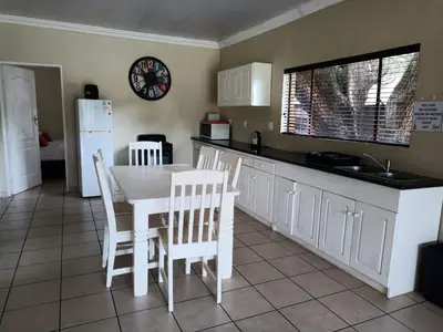 a kitchen with a white table and white chairs at Riverside Lodge - Loerie in Cobalt