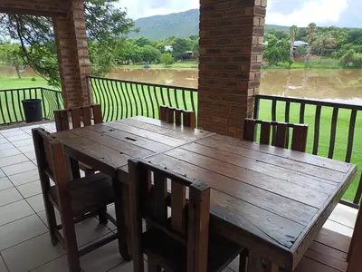 a wooden table and chairs on a patio with a view at Riverside Lodge - Loerie in Cobalt