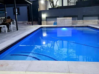 a blue swimming pool with a person sitting in a chair next to it at Batuka Damview Lodge in Tshakhuma