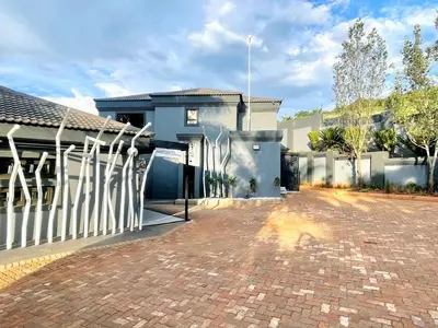 a house with a white fence and a brick driveway at Batuka Damview Lodge in Tshakhuma