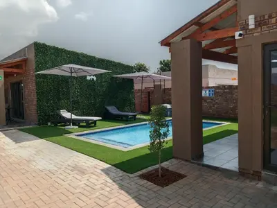 a courtyard with a swimming pool with umbrellas at Lavani Lodge in Lerulaneng